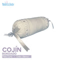 Cojín cilíndrico bordado para cuna en color blanco con cintas decorativas.
