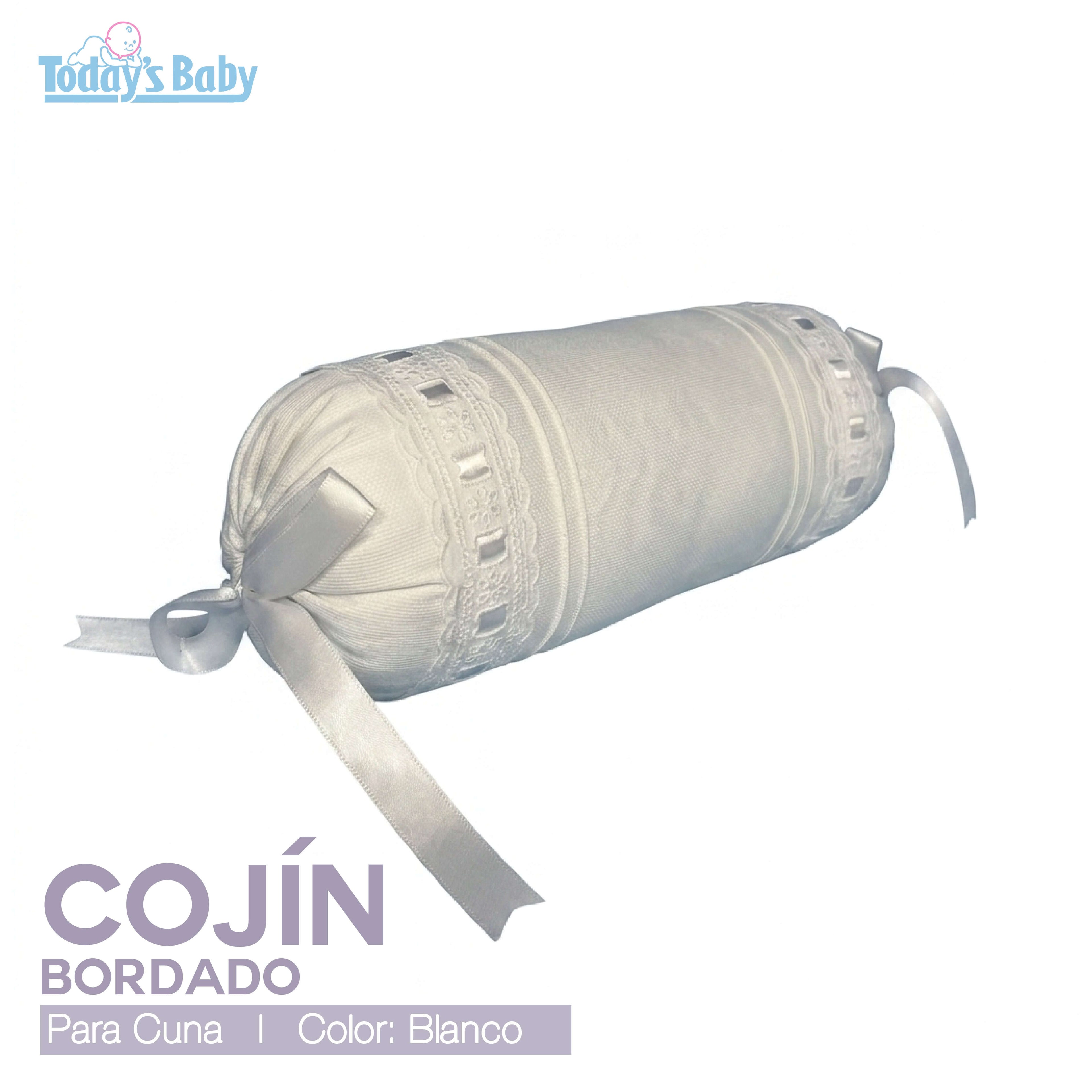 Cojín cilíndrico bordado para cuna en color blanco con cintas decorativas.